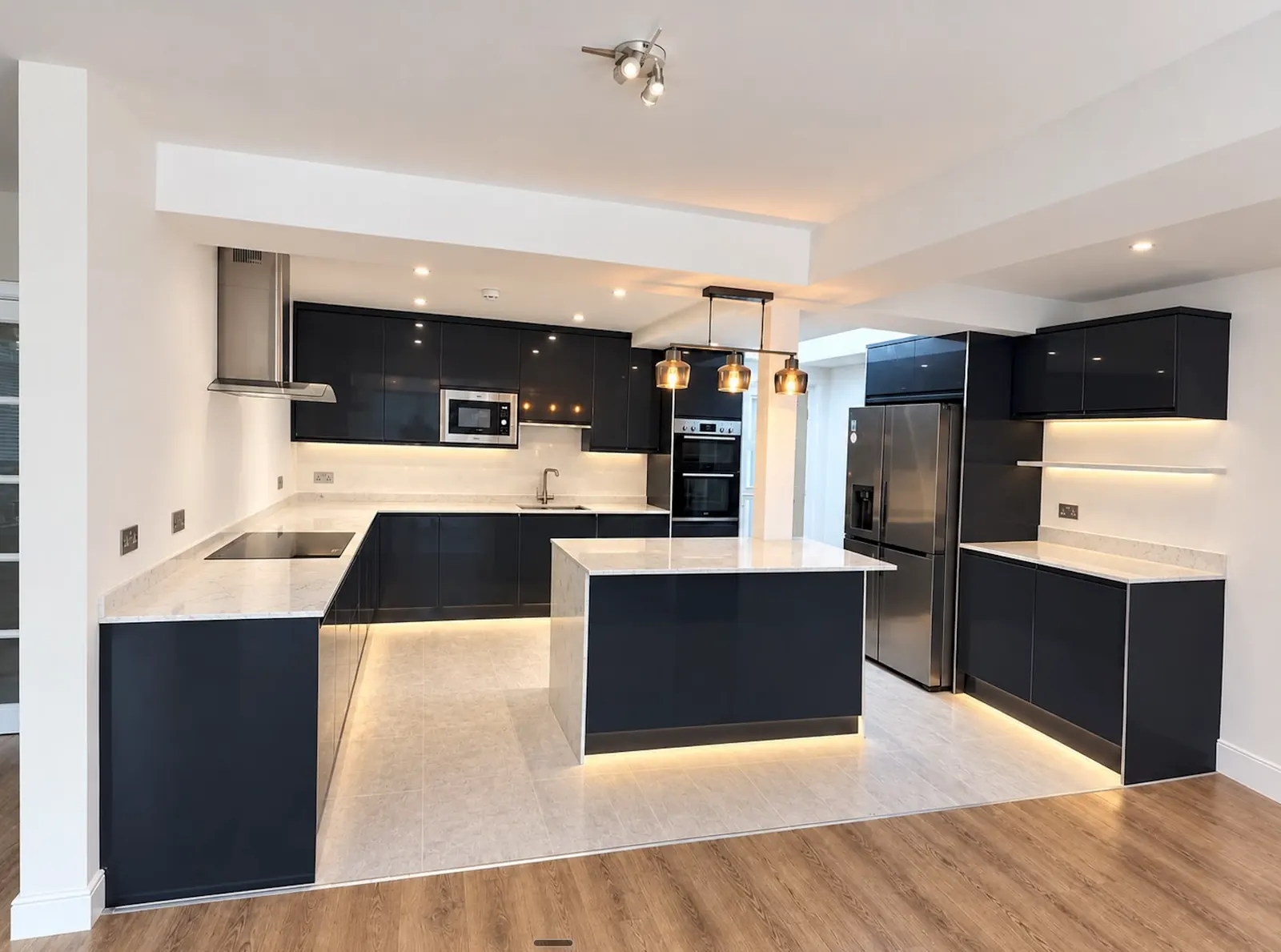 Dark kitchen with pendant lights, under-cabinet lighting and illuminated plinths