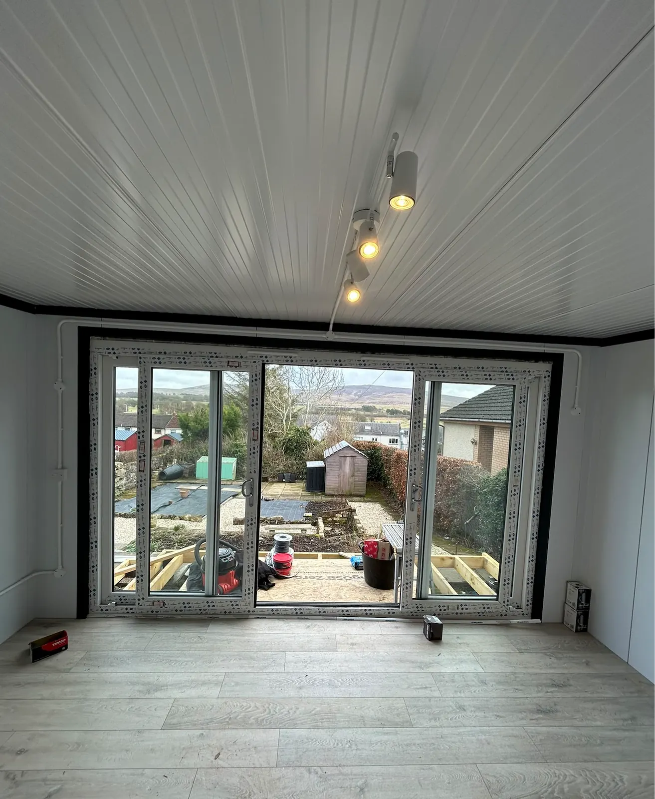 Garden room interior with ceiling track lights and surface-mounted conduit