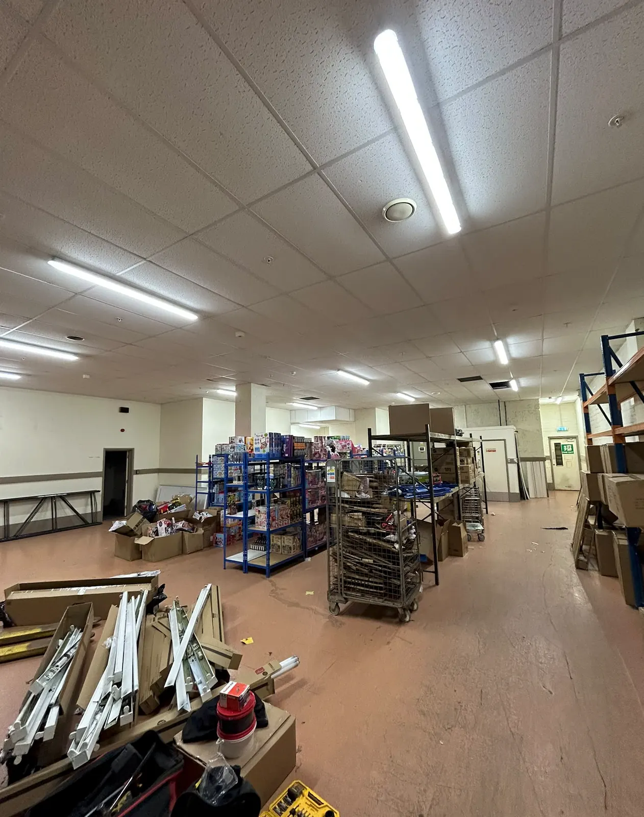 Stockroom with ceiling-mounted batten lights above shelving and storage cages