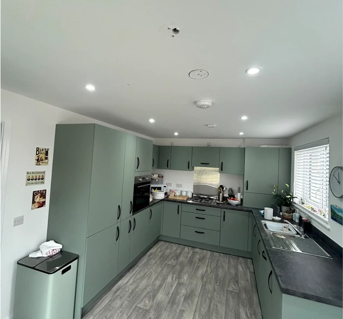 Recessed ceiling downlights above green kitchen cabinets