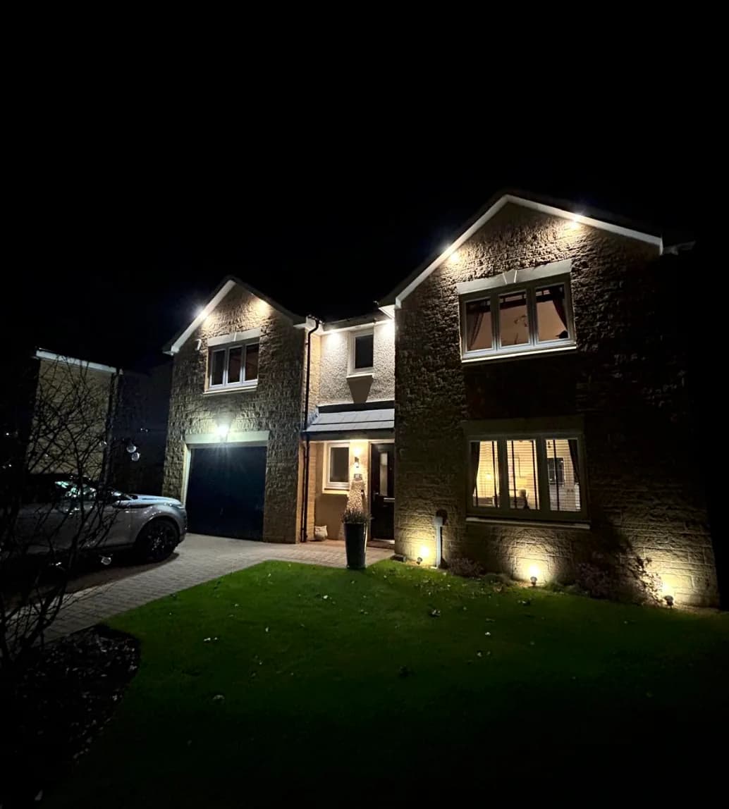 Exterior lights illuminating a two-storey stone house at night
