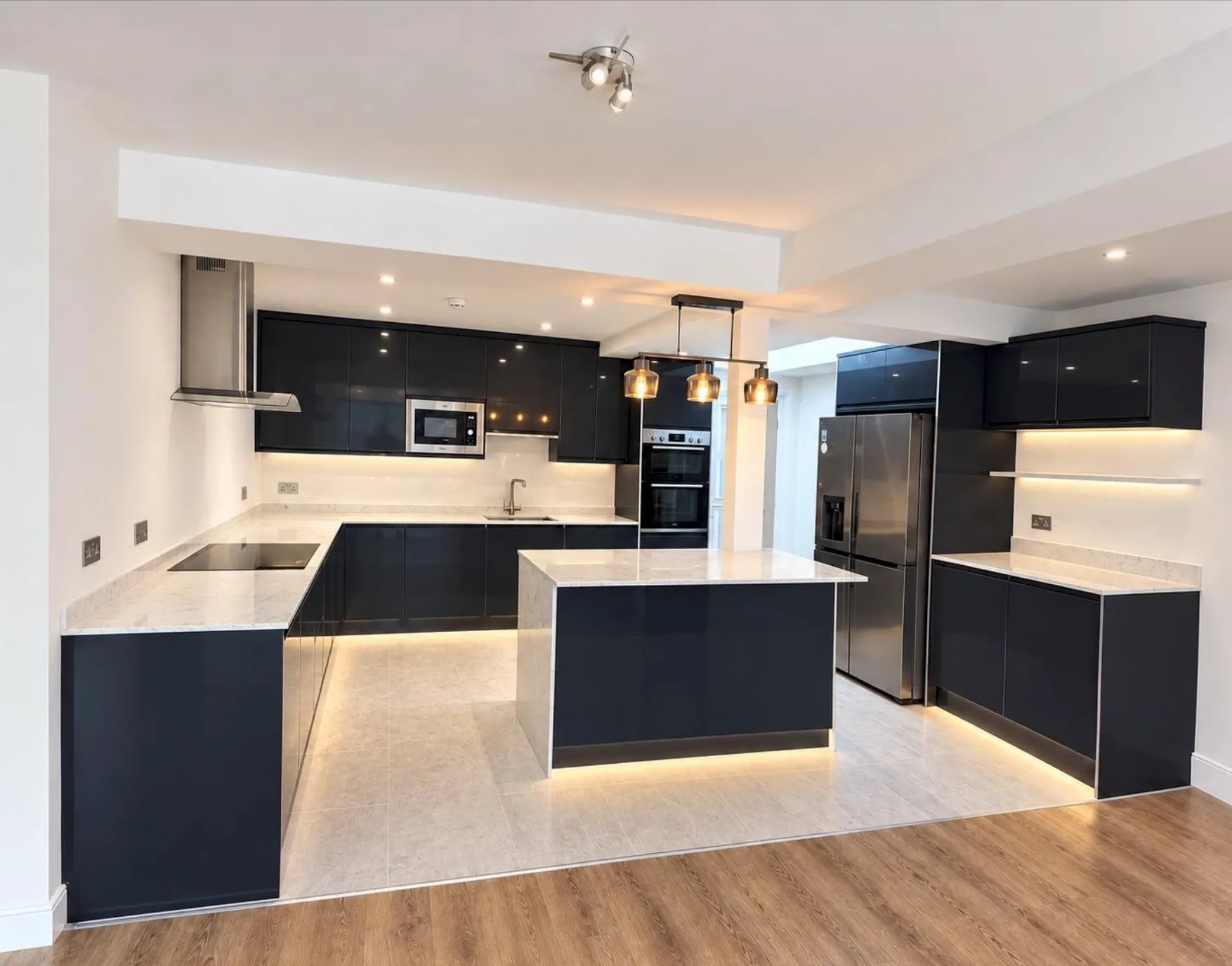 Dark kitchen cabinets with pendant lights, under-cabinet lighting and illuminated plinths