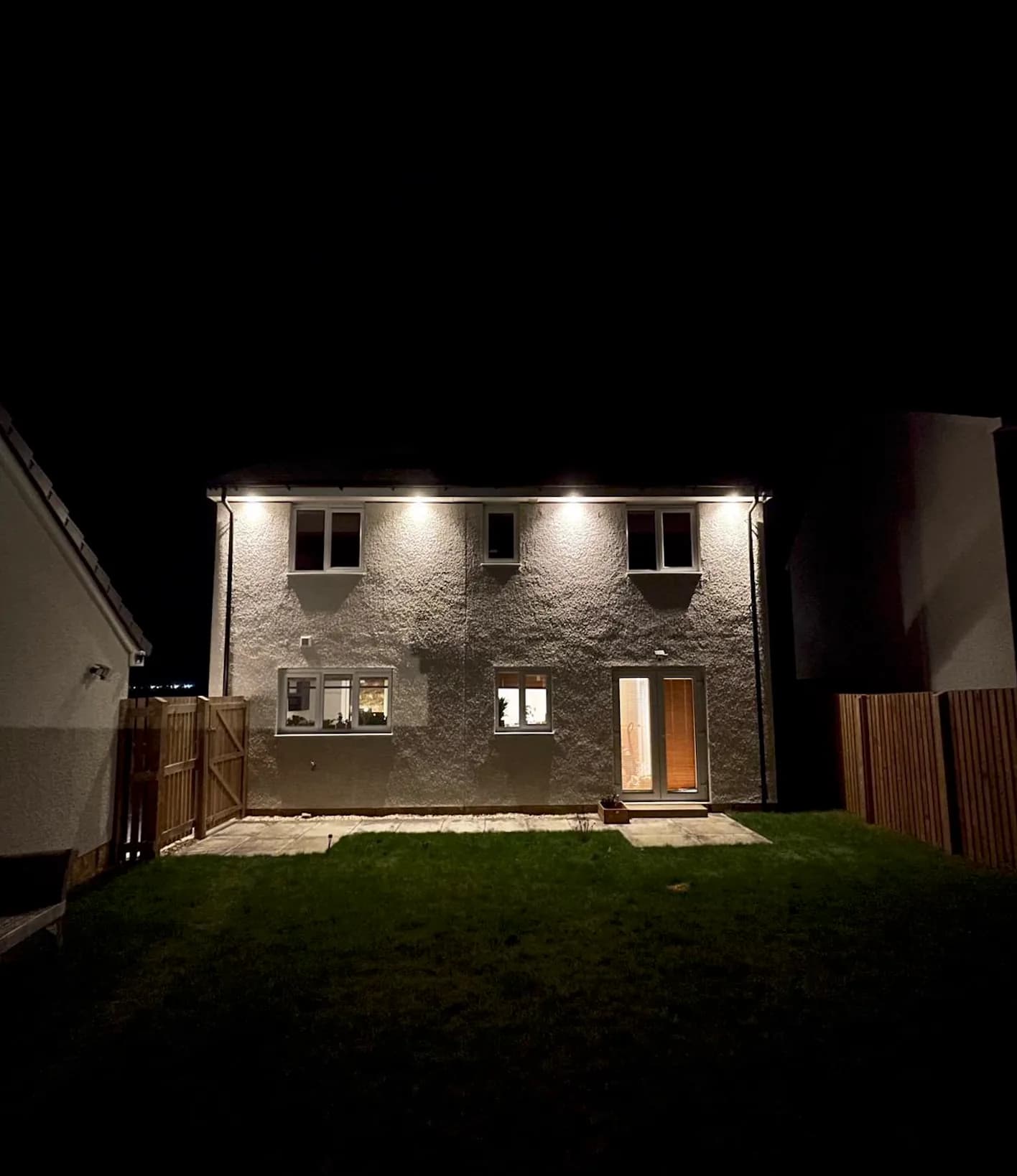 Exterior downlights illuminating the rear of a house at night